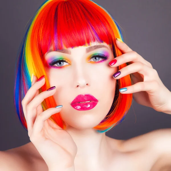 Красива жінка в барвистій перуці і показує барвисті нігті — стокове фото