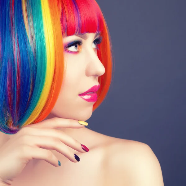 Hermosa mujer vistiendo peluca colorida y mostrando uñas coloridas —  Fotos de Stock