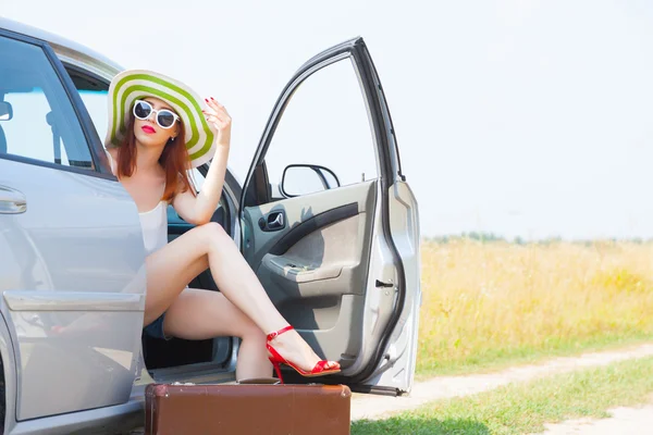 Vrouw zitten in auto met koffer — Stockfoto