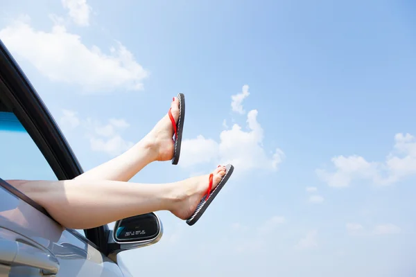 Női lábak lóbáló-ból kocsi ablak — Stock Fotó