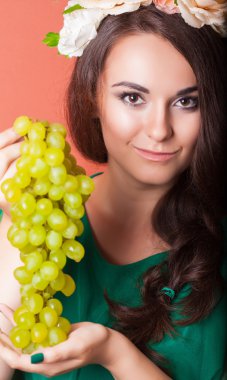 çelenk takmış ve Yeşil üzüm tutan genç bir kadın