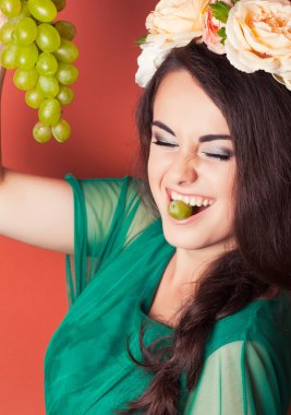 çelenk takmış ve Yeşil üzüm tutan genç bir kadın