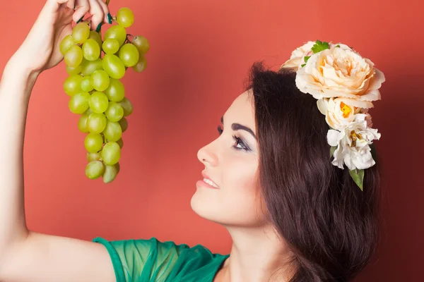 Mujer joven con corona y sosteniendo uvas verdes — Foto de Stock