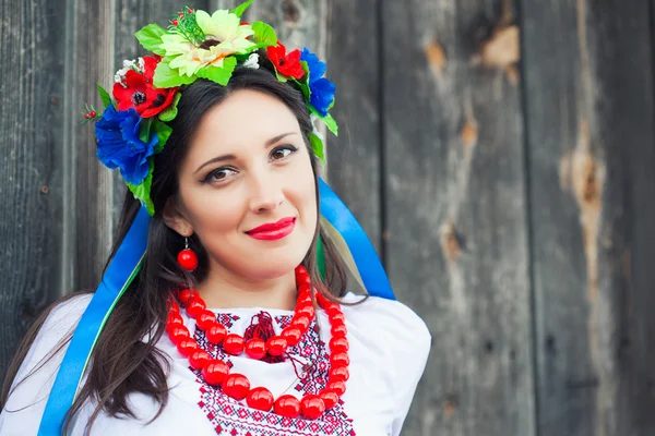 Mulher vestindo roupas ucranianas nacionais sentada em cabana de madeira — Fotografia de Stock