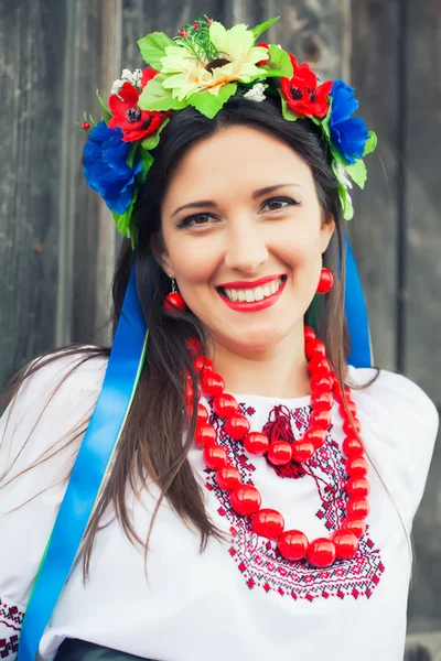 Woman wearing national ukrainian clothes sitting in wooden hut — Stock Photo, Image