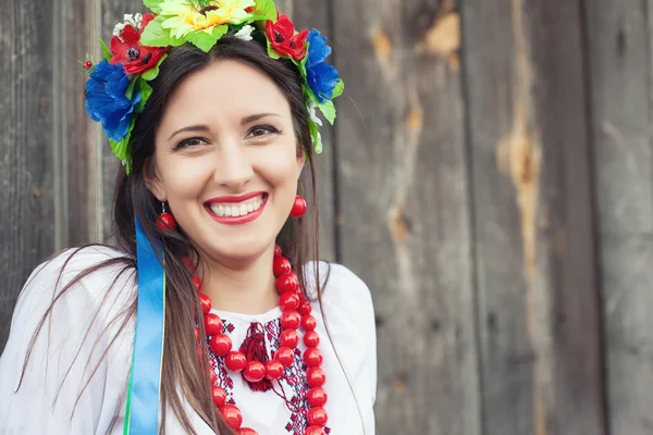 Woman wearing national ukrainian clothes sitting in wooden hut — Stock Photo, Image