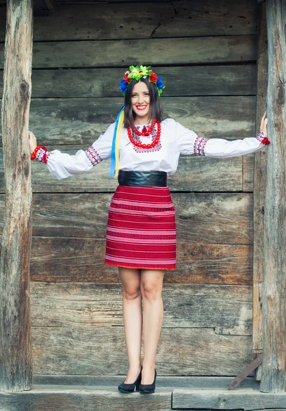 Femme portant des vêtements ukrainiens nationaux près d'une cabane en bois — Photo