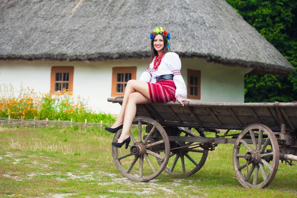 Kvinna som bär nationella ukrainska kläder sitter på gamla häst ritade trä vagn — Stockfoto