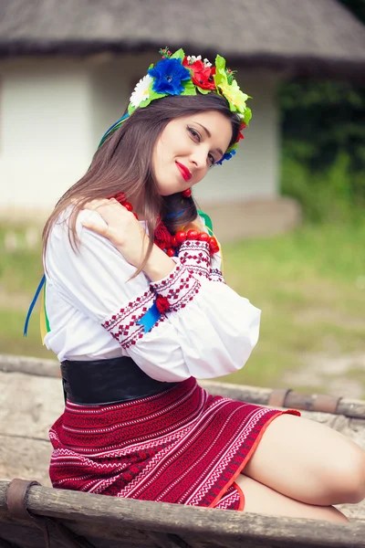 Woman wearing national ukrainian clothes sitting on old horse drawn wooden cart — Stock Photo, Image