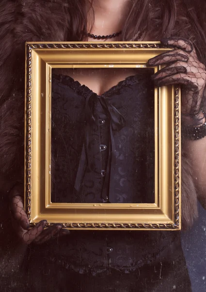 Mujer sosteniendo marco dorado vintage — Foto de Stock