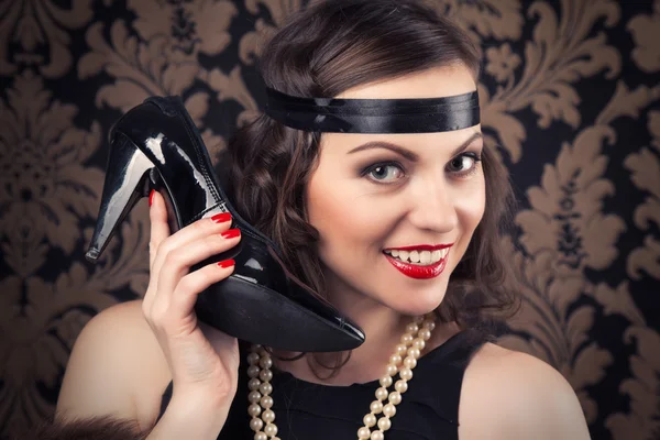 Mujer sosteniendo un zapato negro como receptor de teléfono — Foto de Stock