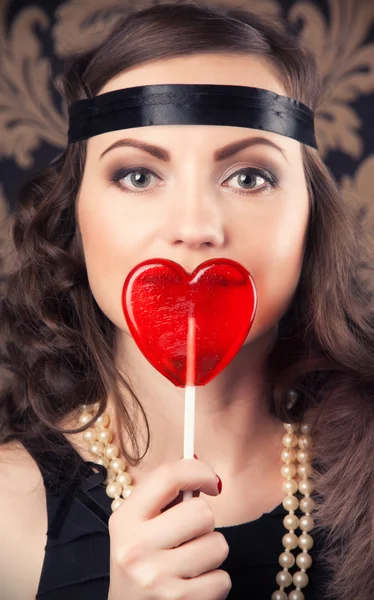 Retro woman holding red heart-shaped lollipop — Stock Photo, Image