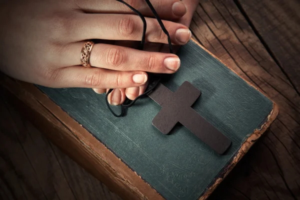 Hands holding vintage cross on Bible — Stock Photo, Image