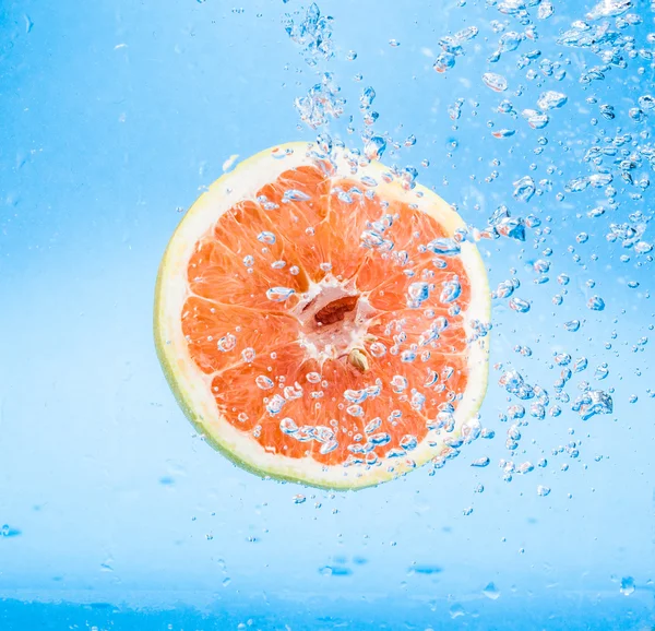 Grapefruit in water with bubbles — Stock Photo, Image