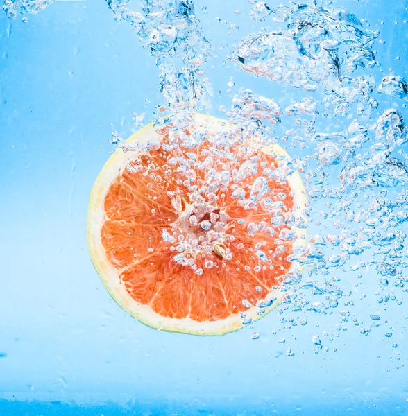 Grapefruit in water with bubbles — Stock Photo, Image