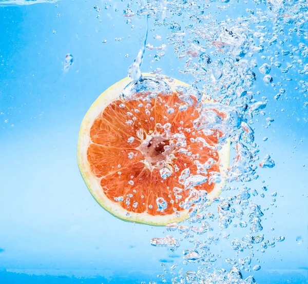 Грейпфрут у воді з бульбашками — стокове фото