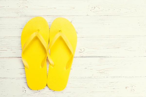 Gelbe Flipflops auf hölzernem Hintergrund — Stockfoto