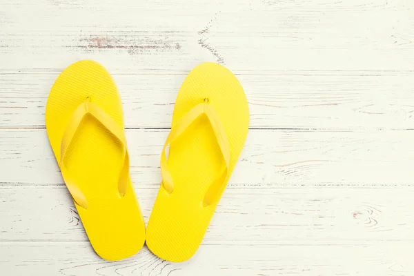 Yellow flip-flops on wooden background — Stock Photo, Image