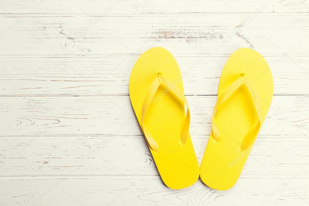 Yellow flip-flops on wooden background