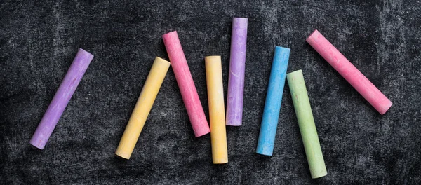 Pieces of school chalk on old black chalkboard — Stock Photo, Image