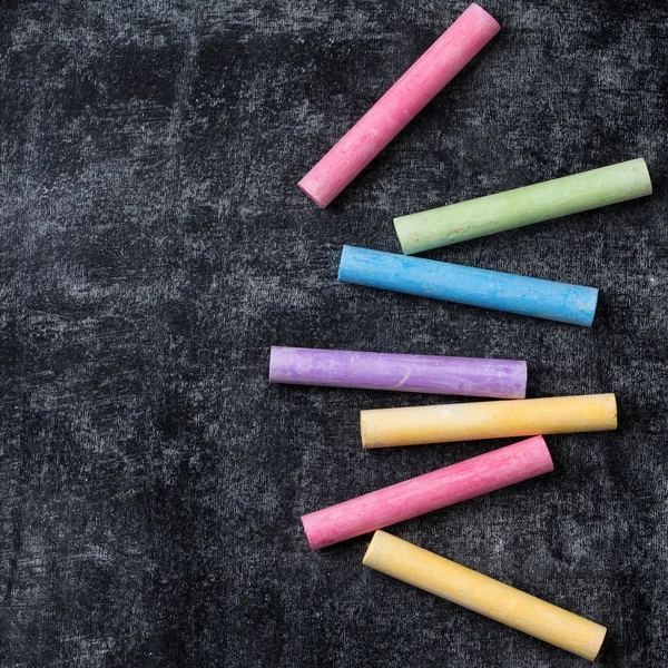 Pieces of school chalk on old black chalkboard — Stock Photo, Image