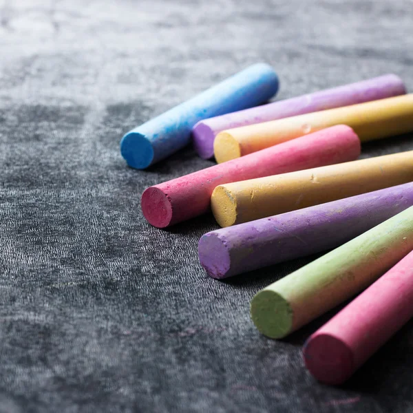 Pieces of school chalk on old black chalkboard — Stock Photo, Image