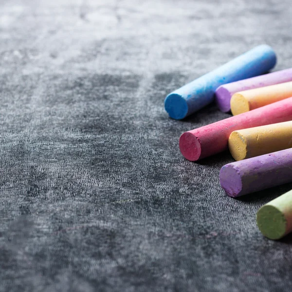 Pieces of school chalk on old black chalkboard — Stock Photo, Image