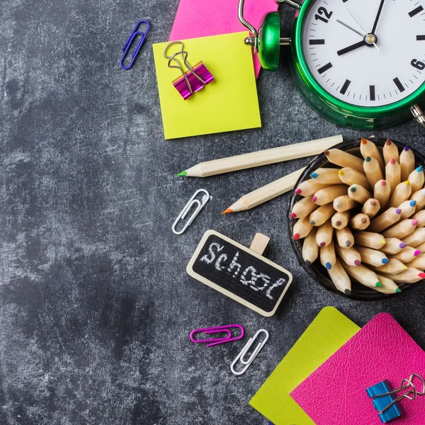 Papelería escolar, lápiz, pluma, nota, reloj despertador en pizarra grunge —  Fotos de Stock