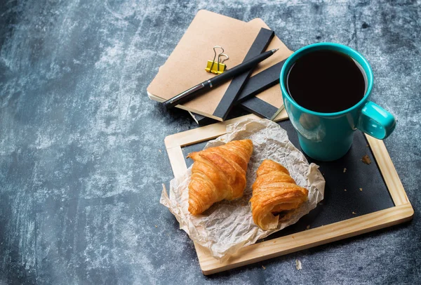 Papeterie d'affaires croissants tasse de café sur tableau noir grunge — Photo