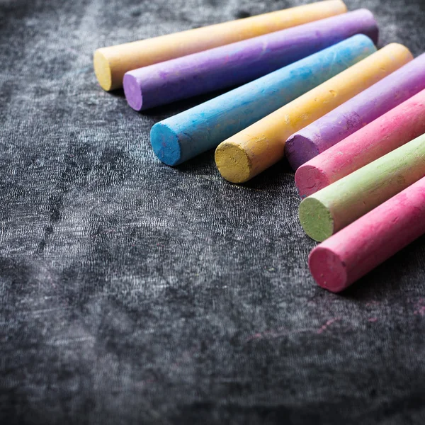 Pieces of school chalk on old black chalkboard — Stock Photo, Image