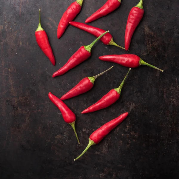 Raw red chili peppers on a black rusty table — Stock Photo, Image