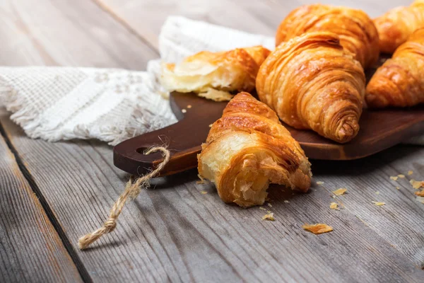 Croissants frais pour le petit déjeuner sur table à découper rustique — Photo