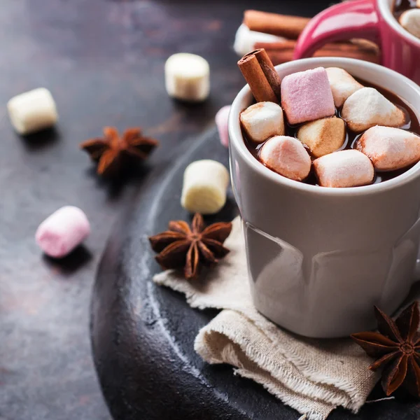 Varm chokolade med skumfiduser og krydderier på grunge mørkt bord - Stock-foto