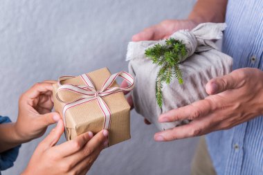 Yaratıcı sıfır noel konsepti. İnsanlar, çevre dostu el yapımı el yapımı el yapımı el yapımı el yapımı el işi kağıtları ve geleneksel Japon tarzı Furoshiki kumaşları ile sarıyorlar. Aile zamanı, şenlik hazırlığı.