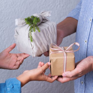 Yaratıcı sıfır noel konsepti. İnsanlar, çevre dostu el yapımı el yapımı el yapımı el yapımı el yapımı el işi kağıtları ve geleneksel Japon tarzı Furoshiki kumaşları ile sarıyorlar. Aile zamanı, şenlik hazırlığı.
