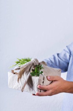 Yaratıcı sıfır noel konsepti. El yapımı hediye paketi veren eller çevre dostu geleneksel Japon tarzı furoshiki kumaşına sarılıyor.
