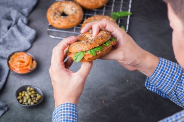 Yemek, öğle yemeği, brunch, tabakta yemek, kaplama konsepti. Genç adam el ele tutuşup füme somon, krem peynir, kapari ve fesleğen yemeye hazır.