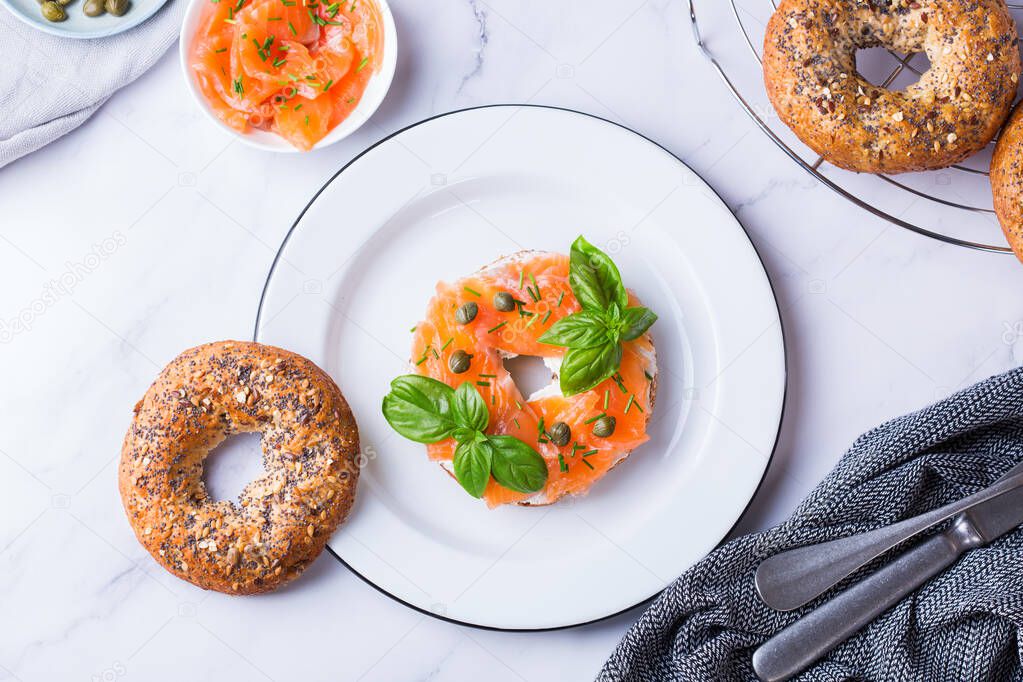 Food, lunch, brunch, meal on a plate, plating concept. Bagels with smoked salmon, cream cheese and capers on a table. Flat lay, top view background. 