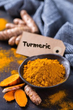 Yiyecek ve içecek, diyet beslenme, sağlık konsepti. Çiğ organik turuncu zerdeçal kökü ve toz, yemek masasında sokağa çıkma yasağı. Hint asıllı düşük kolesterol baharatları