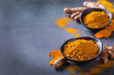 Yiyecek ve içecek, diyet beslenme, sağlık konsepti. Çiğ organik turuncu zerdeçal kökü ve toz, yemek masasında sokağa çıkma yasağı. Hint asıllı düşük kolesterol baharatları. Boşluk arkaplanı kopyala