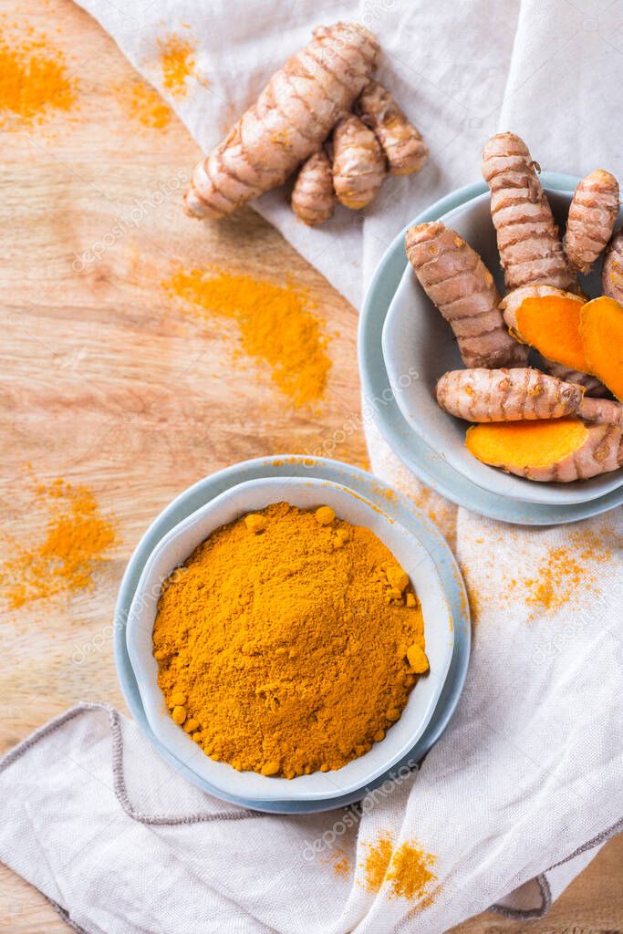 Food and drink, diet nutrition, health care concept. Raw organic orange turmeric root and powder, curcuma longa on a cooking table. Indian oriental low cholesterol spices.