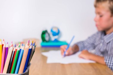 Evlat, öğrenci çalışıyor, öğreniyor, evden ders çalışıyor, not defterine not alıyor. Öğrenci, eğitim, evde kalmak, evde eğitim kavramı.