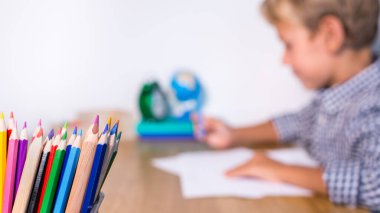 Evlat, öğrenci çalışıyor, öğreniyor, evden ders çalışıyor, not defterine not alıyor. Öğrenci, eğitim, evde kalmak, evde eğitim kavramı.