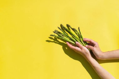 Taze kuşkonmaz, güneşli, canlı, sert ışık ve gölgelerle. Yaratıcı pop sanat tasarımı konsepti. Sarı arkaplanı aydınlatan moda kopyalama alanı