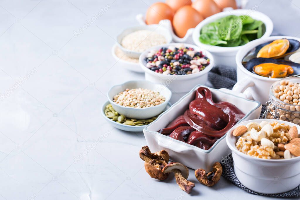 Healthy nutrition dieting concept. Assortment of foods high in iron. Beef liver, spinach, eggs, legumes, nuts, mushrooms, quinoa, sesame, pumpkin seeds, soy beans, seafood. 
