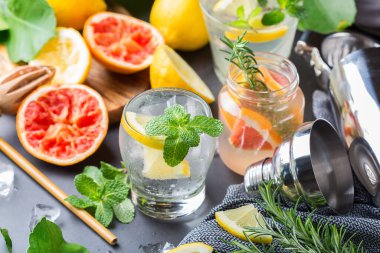 Limonlu, greyfurtlu, naneli, biberiyeli ve buzlu maden suyu kokteyli. Yaz ferahlatıcı içecekler, modaya uygun sıfır atık aksesuarları, bambu kamışları ve ağ torbalarıyla içecekler..