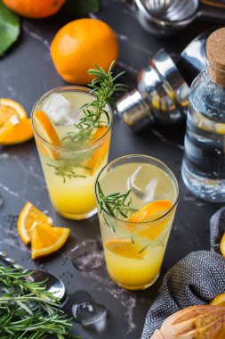 Portakallı, biberiyeli ve buzlu sert maden suyu kokteyli. Yaz ferahlatıcı içecekler, siyah bir masada içmek.
