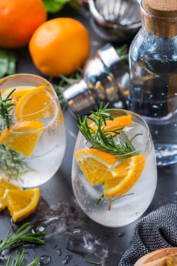 Portakal, biberiye ve barmen aksesuarlarıyla sert maden suyu kokteyli.