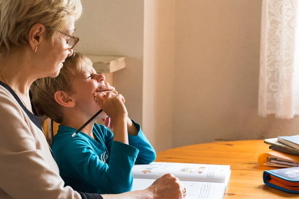 Homeschooling grandmother teaching smart boy, child at home