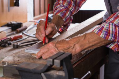 Marangoz tezgahta, marangozluk aletlerinde ve ahşap işçiliğinde çalışıyor.